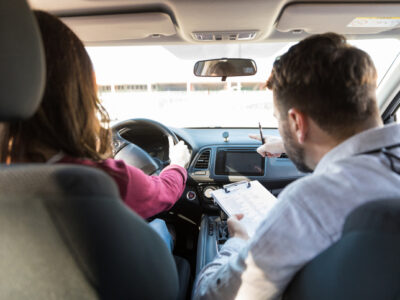 Rear view of mid adult teacher pointing while woman parking car